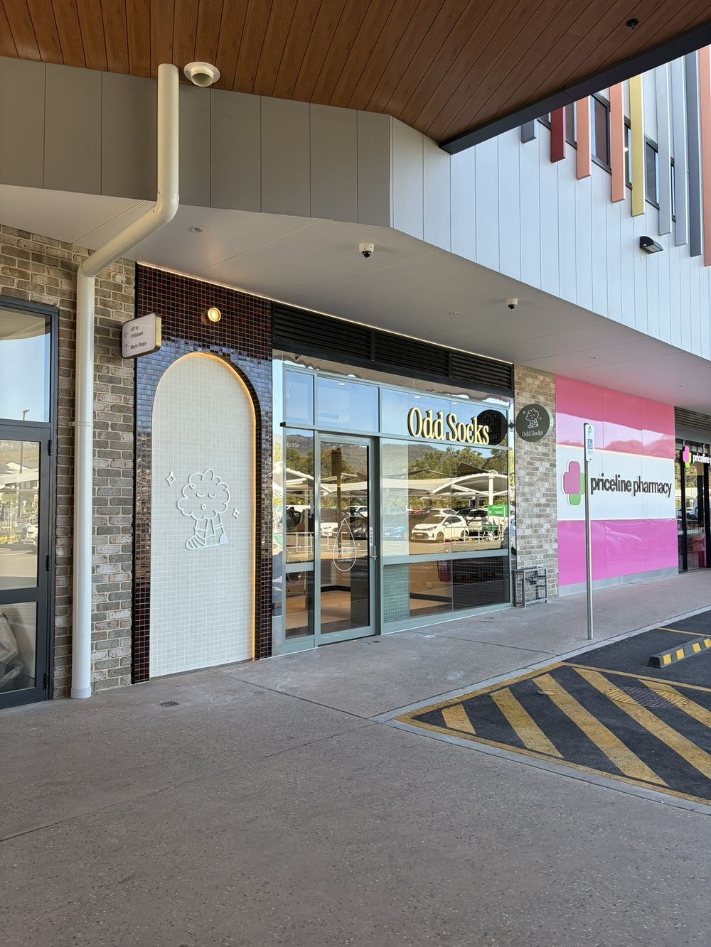 Odd Socks at Calderwood Village, directly beside Priceline Pharmacy, with the shopping centre carpark out front.